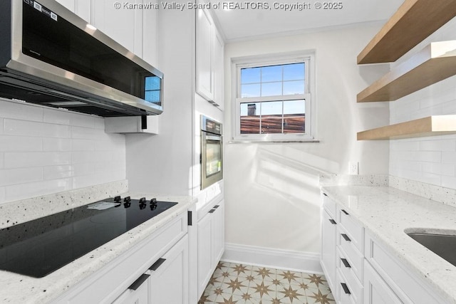 kitchen featuring stainless steel appliances, light stone countertops, white cabinets, and decorative backsplash