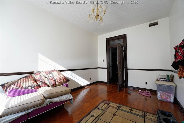 living room with hardwood / wood-style flooring, a textured ceiling, and an inviting chandelier