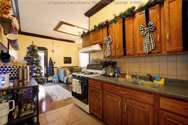 kitchen featuring sink, crown molding, light tile patterned floors, tasteful backsplash, and white gas stove