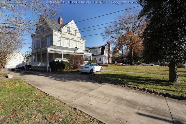 view of side of home featuring covered porch and a lawn