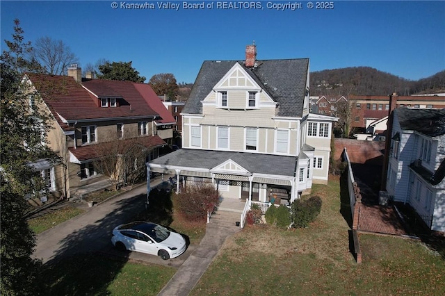 rear view of property featuring a porch and a yard