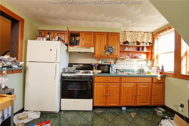 kitchen with tasteful backsplash, sink, range with gas stovetop, and white fridge