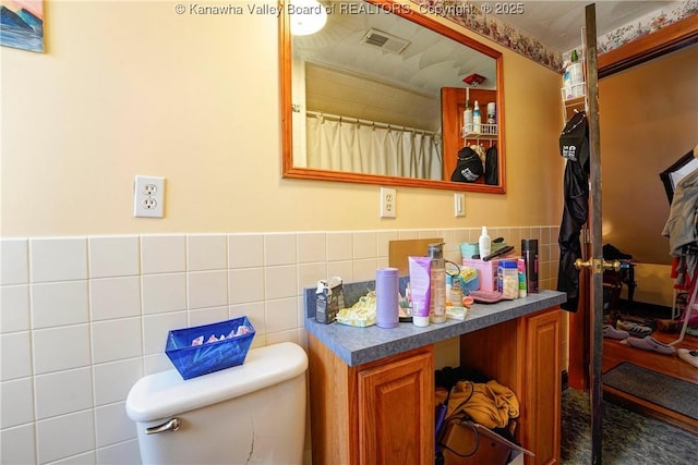 bathroom with tile walls, vanity, and toilet