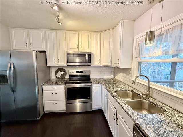 kitchen with sink, white cabinetry, pendant lighting, stainless steel appliances, and backsplash