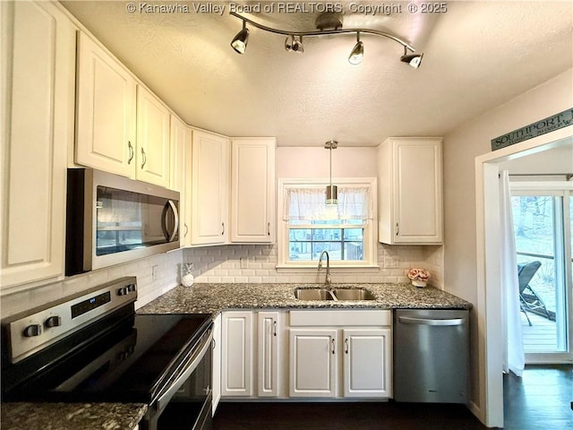 kitchen with appliances with stainless steel finishes, decorative light fixtures, sink, and white cabinets