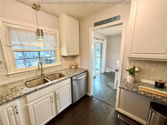 kitchen with sink, dishwasher, white cabinetry, hanging light fixtures, and dark stone counters