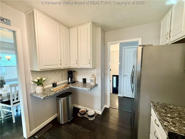 kitchen featuring decorative backsplash, stainless steel refrigerator, white cabinets, and stone counters