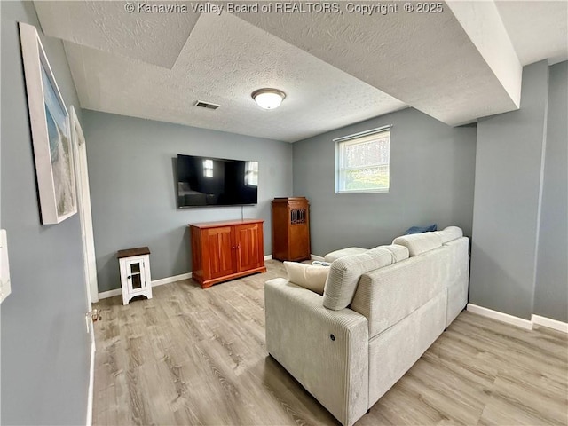 living room with a textured ceiling and light wood-type flooring