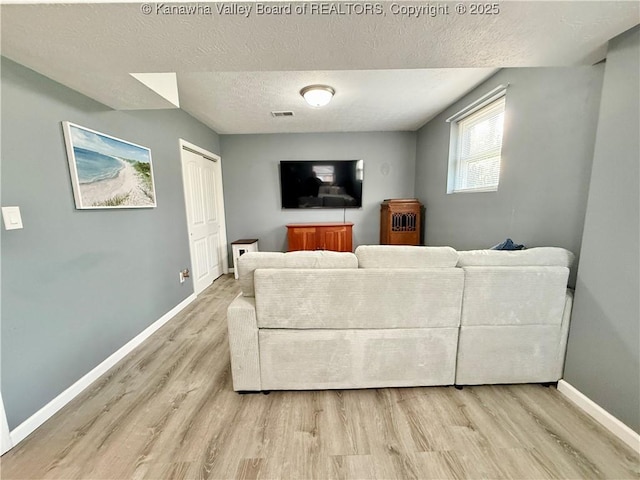 living room featuring light hardwood / wood-style flooring and a textured ceiling