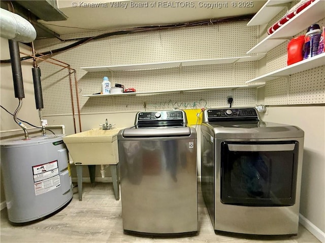 laundry room featuring light hardwood / wood-style floors, washer and clothes dryer, sink, and water heater