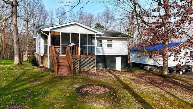 rear view of house with cooling unit, a lawn, and a sunroom