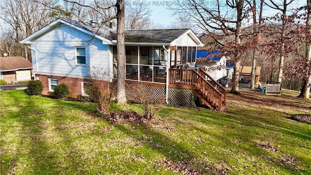 rear view of house featuring a yard, a deck, and a sunroom