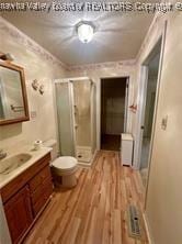 bathroom with a shower with door, wood-type flooring, vanity, and toilet