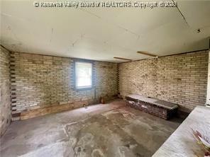 misc room with concrete flooring and brick wall