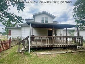 rear view of house featuring a wooden deck and a lawn