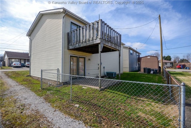 view of front of home with a wooden deck, central AC unit, and a front yard