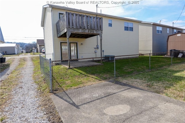 back of property with central AC unit, a yard, and a balcony