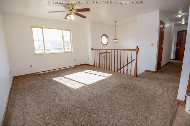 spare room featuring a baseboard heating unit, ceiling fan, and carpet