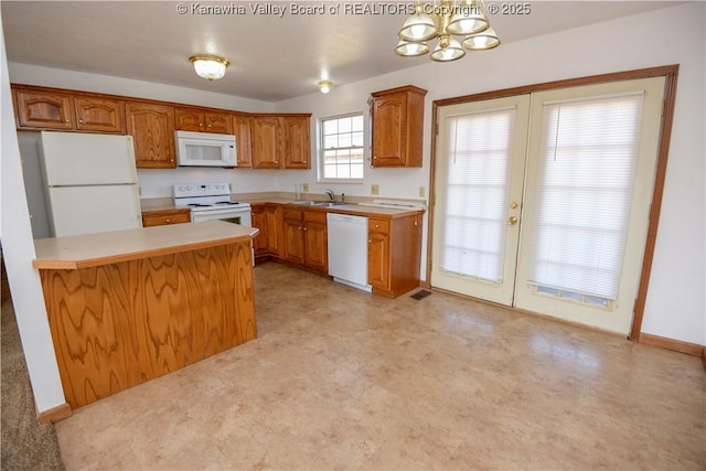 kitchen featuring white appliances, kitchen peninsula, sink, and hanging light fixtures