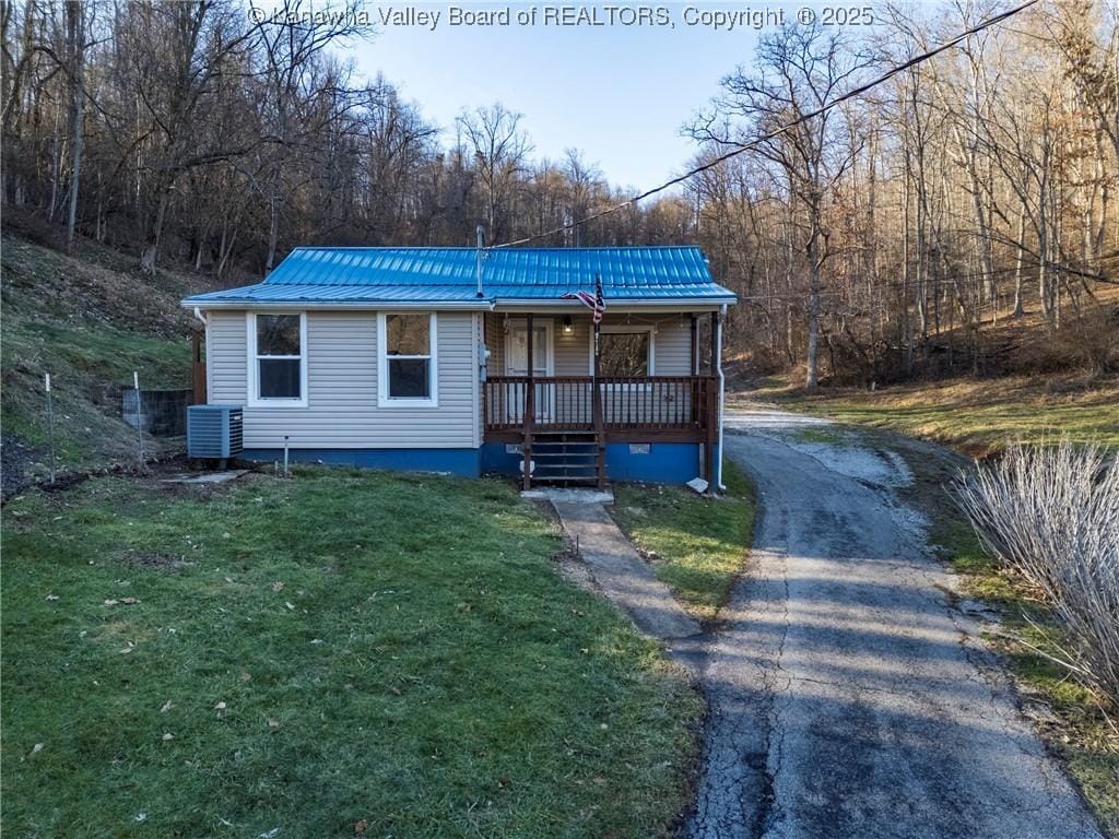 view of front of property featuring a front yard, central AC unit, and covered porch