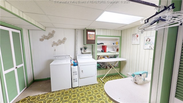 washroom with washing machine and dryer and wooden walls