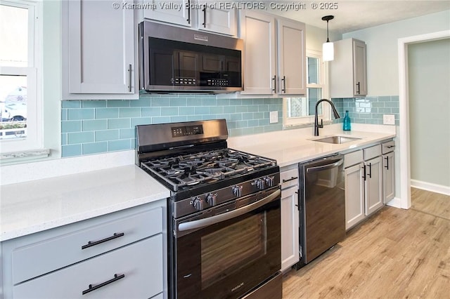 kitchen featuring appliances with stainless steel finishes, pendant lighting, sink, gray cabinetry, and light hardwood / wood-style floors