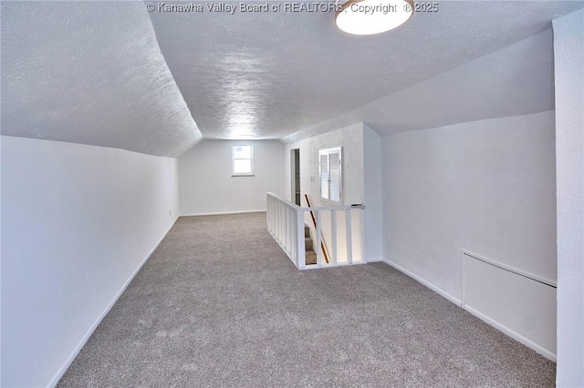 bonus room featuring vaulted ceiling, carpet, and a textured ceiling