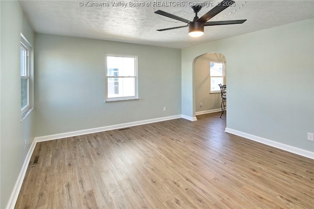 unfurnished room with ceiling fan, a textured ceiling, and light wood-type flooring