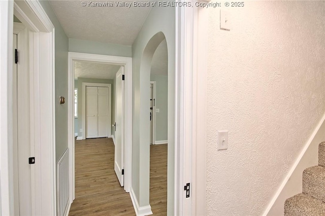 hallway with wood-type flooring and a textured ceiling