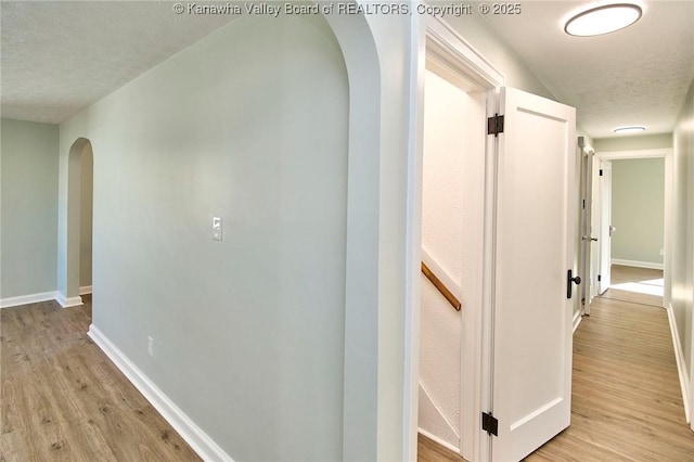 corridor with light hardwood / wood-style floors and a textured ceiling