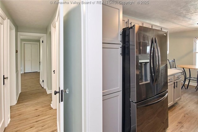 kitchen featuring white cabinetry, a textured ceiling, light hardwood / wood-style floors, and stainless steel fridge with ice dispenser