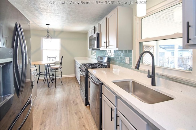 kitchen featuring tasteful backsplash, sink, hanging light fixtures, stainless steel appliances, and a textured ceiling