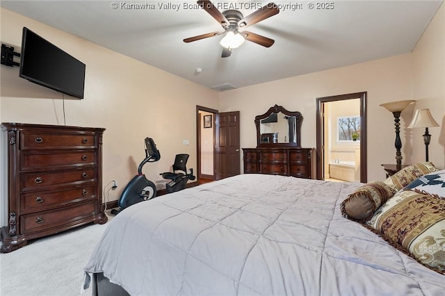 carpeted bedroom with ensuite bath and ceiling fan