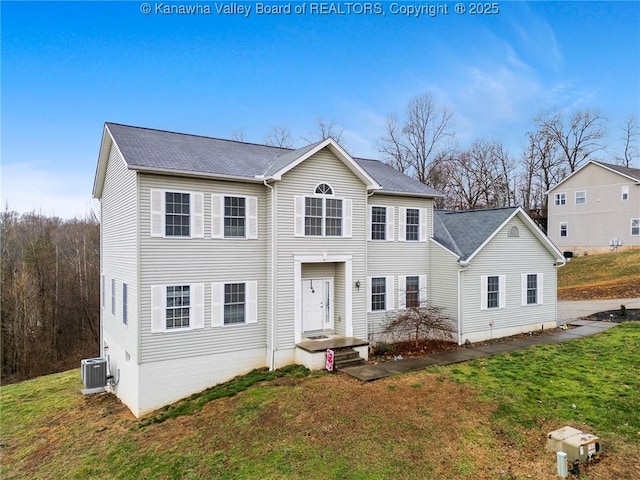 view of front of home with central AC unit and a front yard