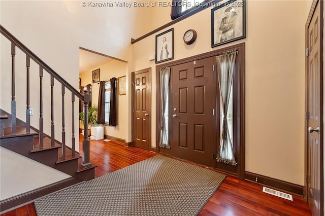 foyer entrance featuring a towering ceiling, dark hardwood / wood-style floors, and a wealth of natural light