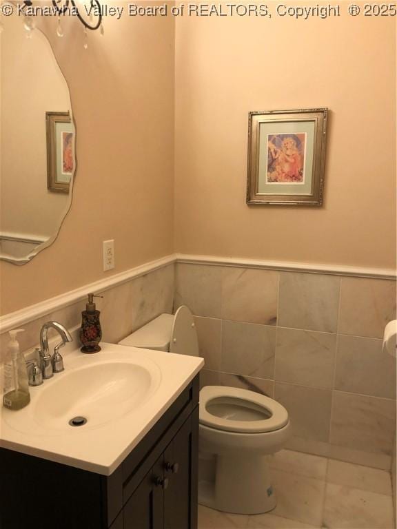 bathroom featuring vanity, toilet, and tile walls