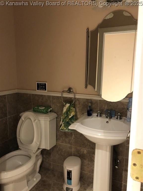 bathroom with tile walls, tile patterned floors, and toilet