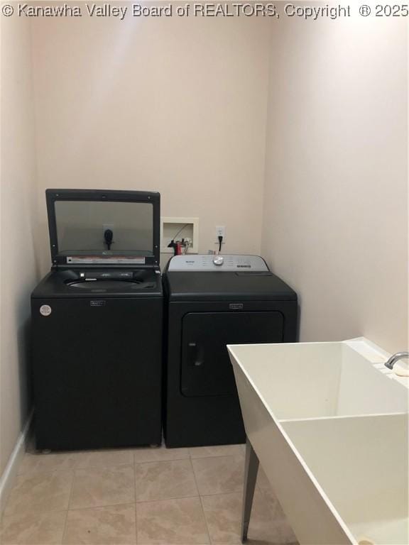 clothes washing area featuring light tile patterned flooring, sink, and washer and dryer