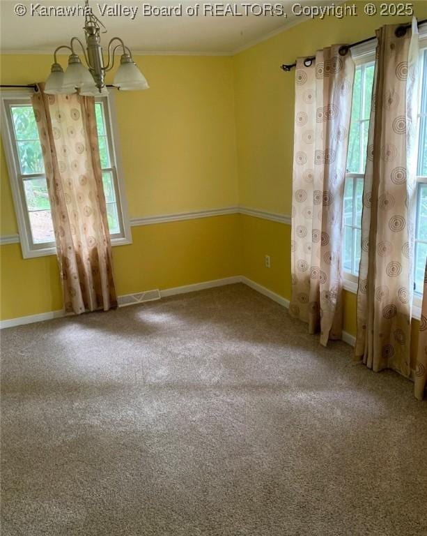 carpeted spare room with ornamental molding and a chandelier