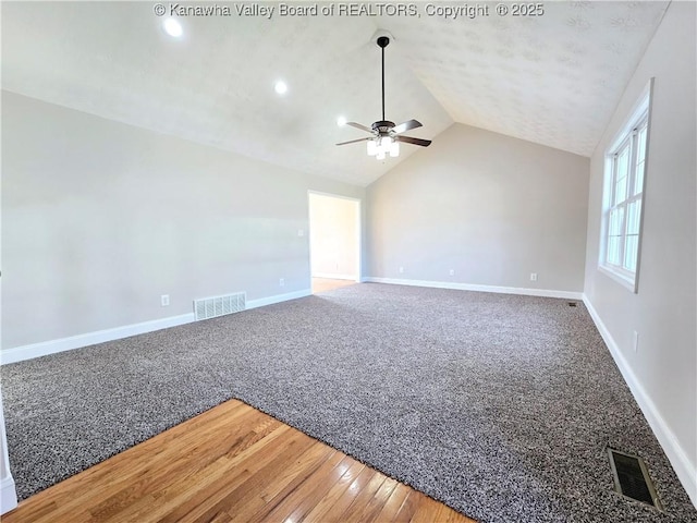 empty room with lofted ceiling, hardwood / wood-style floors, and ceiling fan