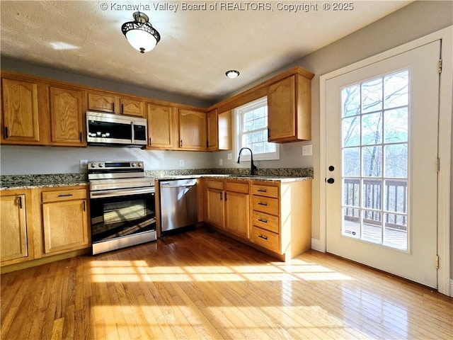 100 Oak Ridge Ln, Huntington, WV 25704 - kitchen with stainless steel appliances, sink, light stone counters, and light hardwood / wood-style floors