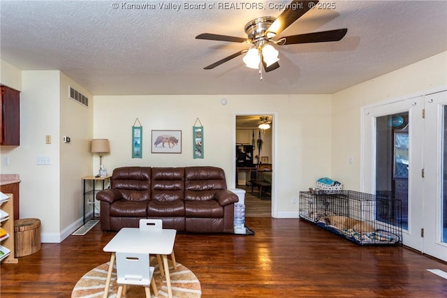 living room with ceiling fan, dark wood-type flooring, and a textured ceiling