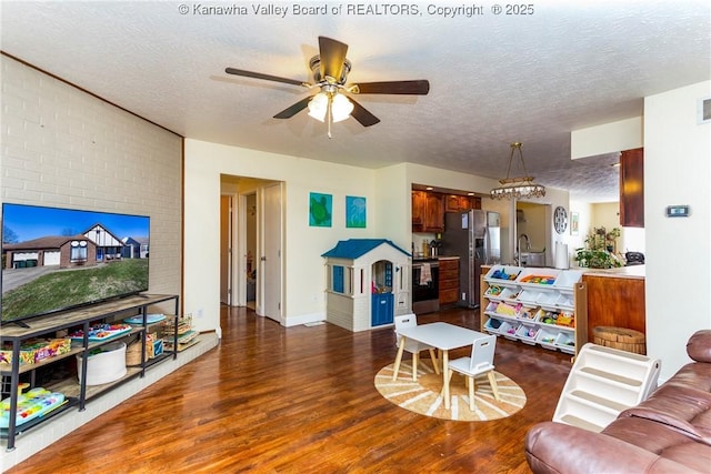 living room featuring dark wood-type flooring, ceiling fan, and a textured ceiling