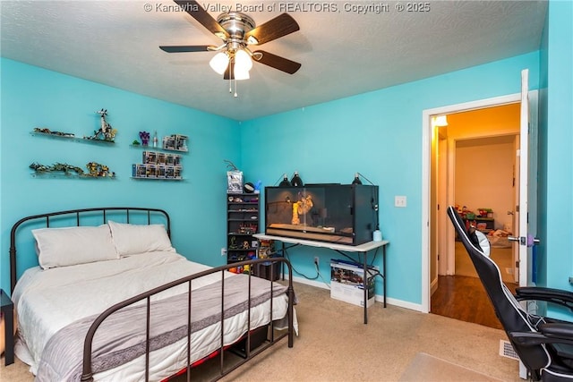 carpeted bedroom featuring ceiling fan and a textured ceiling