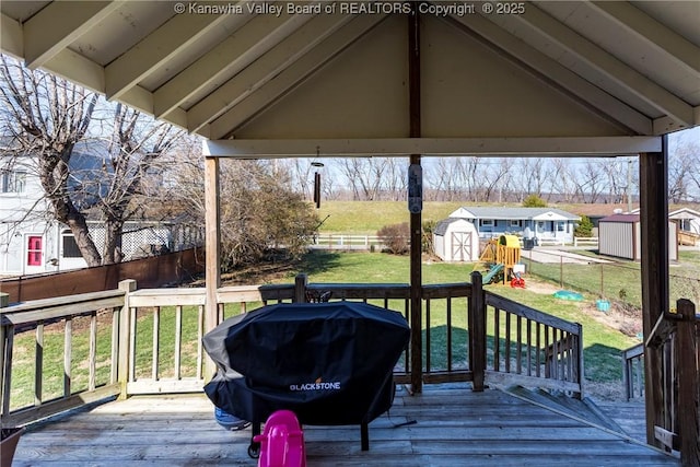 wooden terrace featuring grilling area, a playground, a shed, and a lawn