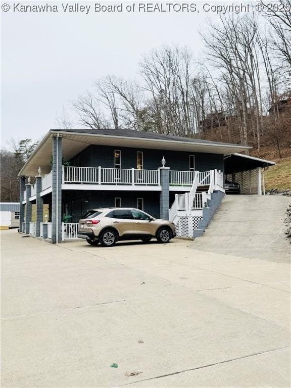 view of front of home with driveway, a carport, and stairway