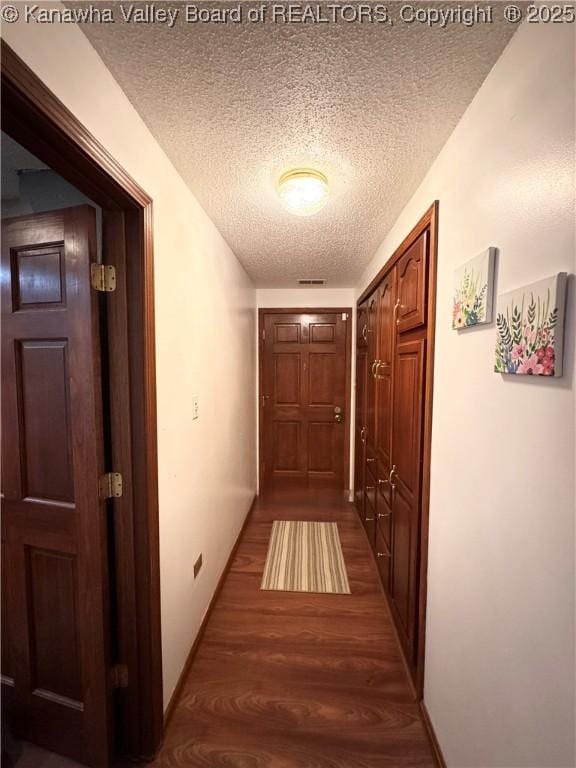 hall with a textured ceiling and dark hardwood / wood-style flooring