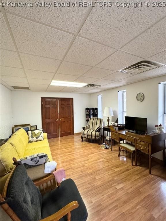 living room with hardwood / wood-style flooring and a paneled ceiling