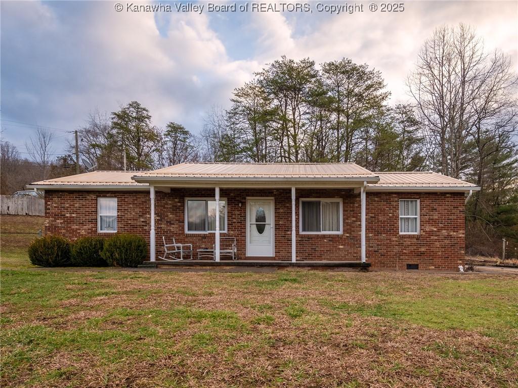 ranch-style home featuring covered porch and a front yard