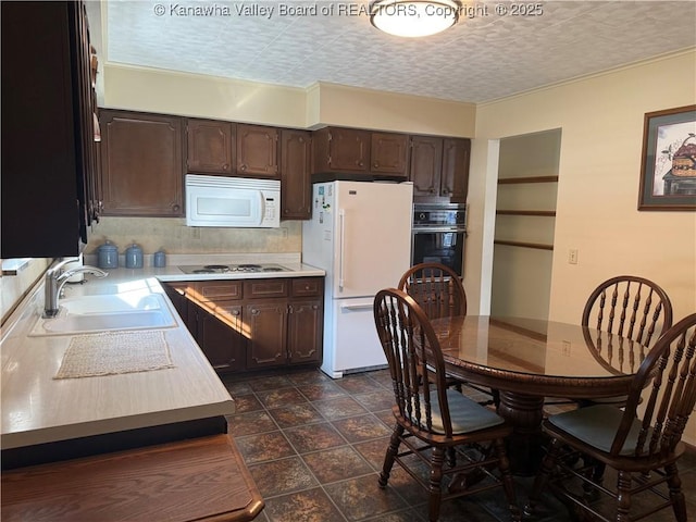 kitchen with dark brown cabinetry, sink, white appliances, tasteful backsplash, and a textured ceiling